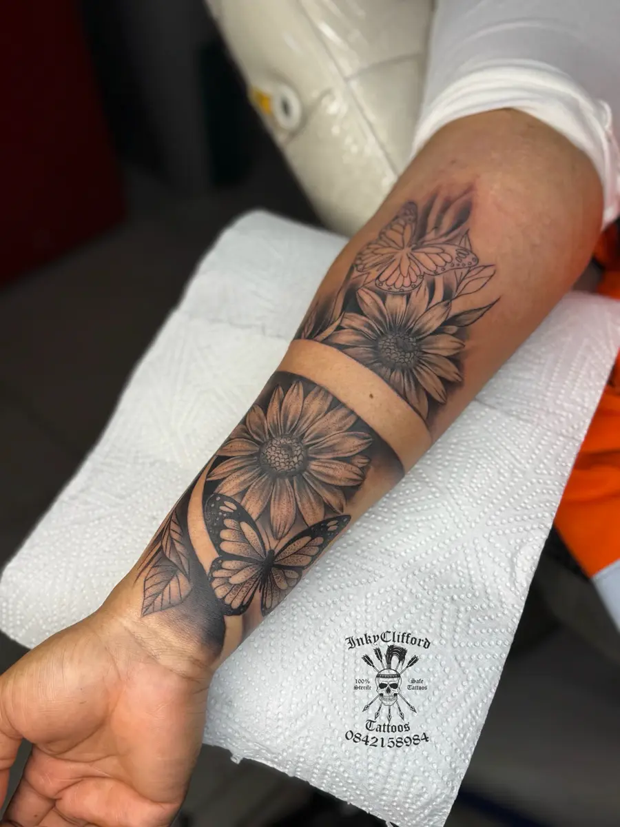 Forearm with floral and butterfly tattoo designs on a white paper towel