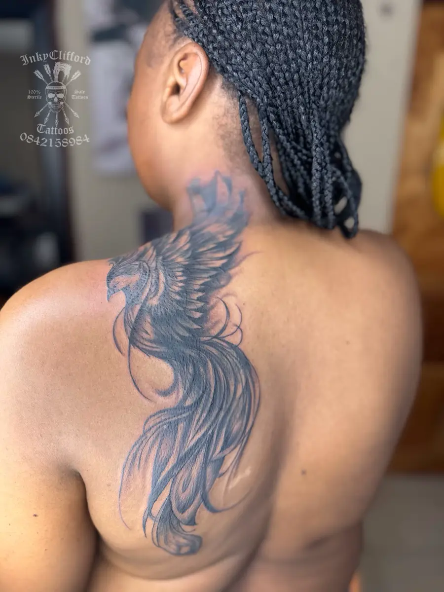Back and profile of a person with braided hair and a large feathered wing tattoo